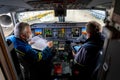 Kyiv, Ukraine - November 25, 2020: Embraer aircraft cockpit. Pilots in medical masks. Technicians diagnose, repair and service the