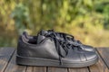 Beautiful new Adidas full black shoes on wooden table, close up