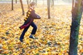 Cute boy in glasses stands in autumn park with gold leaves, holds book in his hands,