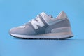 New Balance 574 light gray sneaker on blue background. Suede and mesh walking, casual sport shoe closeup. Illustrative editorial Royalty Free Stock Photo