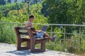 An unidentified business man with his outer clothes removed sits outdoors, drinks coffee and uses a laptop.