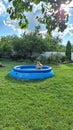 Kyiv, Ukraine - 07.21.2023: A teenager bathes in an inflatable pool in the middle of a green garden and a cottage. Rest of