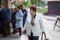 Kyiv, Ukraine, 02.05.2020: A woman wearing a medical mask with packages in her hands. A queue of people wearing medical masks at