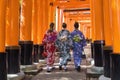 three European women in Kimono walking through Torii path at Fushimi Inari-Taisha Shrine, Kyoto, Japan