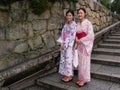 Two girls dressed in the traditional colored kimono on the staircase of a Kyoto temple