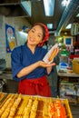 KYOTO, JAPAN - JULY 05, 2017: Unidentified smiling woman holding in her hand a brochette, sold at Nishiki Market in