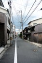 Narrow rural street in city of Kyoto with old traditional japanese buildings made of wood and crooked power poles