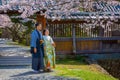 Unidentified Japanese Couple in traditional Kimono dress in a Japanese garden with full bloom cherry