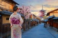 Scenic cityscape of Yasaka pagoda in Kyoto with a young Japanese woman in a traditional Kimono dress in full bloom cherry blossom Royalty Free Stock Photo