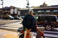 Portrait of back of old Asian man standing on sidewalk waiting to cross street