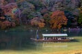 Unidentified tourists on wooden boat enjoy autumn colors along Hozu-gawa river at Arashiyama