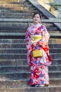 KYOTO, JAPAN - NOVEMBER, 8, 2019: Beautiful and Serene Japanese Lady Posing in Geisha Kimono On Shrine Stairway in Kyoto Streets,