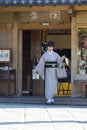 KYOTO, JAPAN - NOVEMBER, 8, 2019: Mature Japanese Female Wearing Traditional Silk Geisha`s Kimono Traveling on Street of Kyoto,