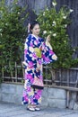 KYOTO, JAPAN - NOVEMBER, 8, 2019: Young Asian Girl Posing in Geisha Kimono in Traditional Japanese Environment in Kyoto, Japan