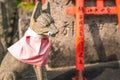 Kyoto, Japan - 05.19.2019: A stone statue of dog with eyeball in its mouth with a pink neck scarf on a tombstone in a cemetery in