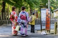 Two female tourists in traditional colorful  japanese kimono taking photo with a selfie stick in front of the bus stop in Kyoto. Royalty Free Stock Photo