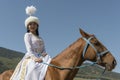 Kyrgyz girl on horse in ethnical outfit at Kyrchin nomadic village