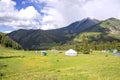 Kyrgyz nomad village on jailoo against a mountain range with snowy peaks and cloudy sky Royalty Free Stock Photo