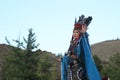 Mongolian woman in shaman and witch costume dances on stage in the mountains. Tyva folk dances