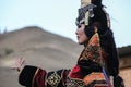 Mongolian woman in shaman and witch costume dances on stage in the mountains. Tyva folk dances