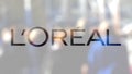 L`Oreal logo on a glass against blurred crowd on the steet. Editorial 3D rendering`
