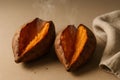 La Castanyada theme. Two baked sweet potatoes split open on a neutral beige background Royalty Free Stock Photo