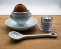 A la coque egg in white ceramic egg cup, spoon and salt shaker. Wooden table, white  background. Royalty Free Stock Photo