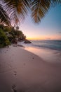 La Digue Island, Seychelles. Beautiful sunset lit colorful sky on exotic tropical sandy beach with foot prints Royalty Free Stock Photo