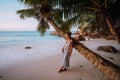 La Digue, Seychelles. A woman near coconut palm tree in a gold sunset light on a tropical beautiful sandy beach Royalty Free Stock Photo