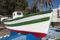 White boat on blue blocks with red and green stripes