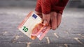 La mano de Tramp con un guante rojo levanta un billete de diez euros