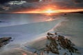 La Pelosa beach in Sardinia at sunrise with a sunburst and rocks in the foreground Royalty Free Stock Photo