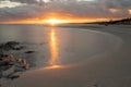 La Pelosa beach in Sardinia at sunrise with a sunburst and rocks in the foreground Royalty Free Stock Photo