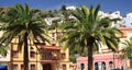 Beautiful coastal town on hill, colorful traditional houses, palm trees, blue sky