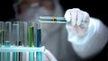 Lab assistant adding liquid from test tube with cross symbol, illegal research Royalty Free Stock Photo