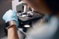 Lab assistant in gloves puts material sample onto slide at microscope working in laboratory