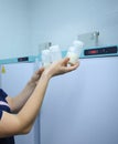 Lab assistant hand holding breast milk storage containers with human milk, freezers on the background. Human Milk Bank laboratory