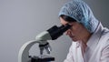 Lab assistant looks at material sample through microscope Royalty Free Stock Photo