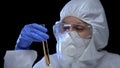 Lab assistant in protective suit studying sample of detergent, research work