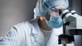 Lab assistant viewing samples in microscope, conducting chemical research