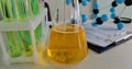 Lab experiment with bubbling yellow liquid in a flask next to test tubes and a molecular model concept Royalty Free Stock Photo