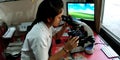 A lab technician girl looking into microscope at laboratory