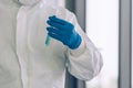 Lab Technician in Personal protective equipment PPE suit holding test tube of Vaccines testing of Virus