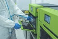 A lab technician places RT-PCR test samples into a DNA or RNA extraction machine. At a testing laboratory