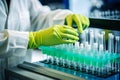 a lab technician in protective green gloves and gloves is looking at small liquids