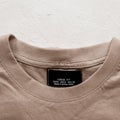 Label and collar of a cotton beige stylish men`s shirt on the white background. Fashionable details of a casual look. Stylish