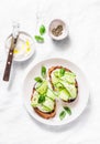 Labne and pickled cucumbers toast on a light background, top view. Sandwiches with soft cheese and cucumber - delicious healthy br