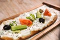 Labneh pizza bread with olives, tomato and cucumber served in wooden board isolated on background top view of Arabic Manaqeesh