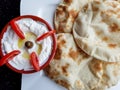 Labneh and tomatoes. Top view of a bowl of labneh, delicious and creamy yoghurt dip with flat bread. Middle eastern food