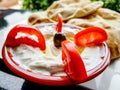 Labneh yoghurt bowl with red tomato slices and an olive decoration
